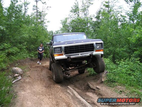 Dark blue 1979 Ford pickup truck with lifted suspension off-roading on a dirt trail