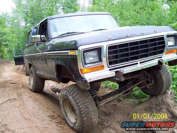 Black Ford Bronco with lifted suspension on a dirt trail, front passenger side wheel elevated