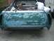 1973 Ford Ranchero - The rear of a green Ford Ranchero shows extensive bodywork, with primer and filler patches across the tailgate and rear fenders.