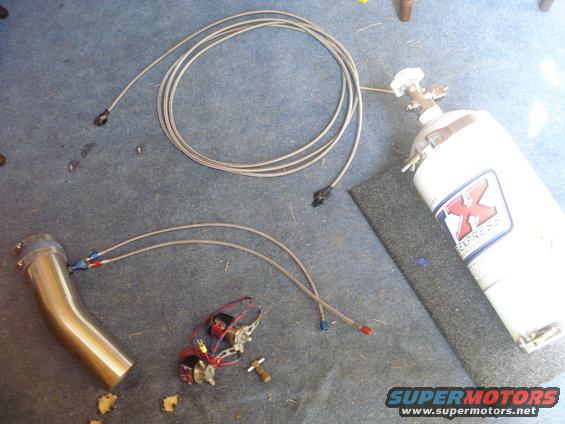 Nitrous oxide tank and exhaust pipe with braided lines and wiring on a blue carpeted surface