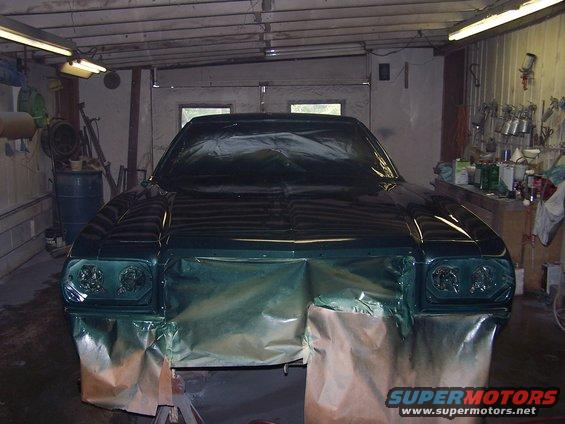 1975 Ford Ranchero front end covered in masking paper and plastic, being prepped for paint in a garage