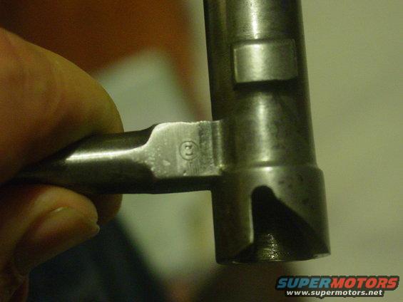 Close-up of a metal part with a circular stamp containing the number 3