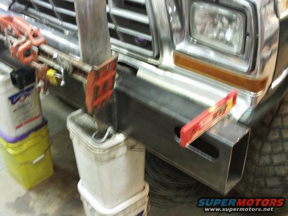 Installing a new steel bumper on a 1979 Ford Bronco. A level is on the bumper, and a hoist is attached