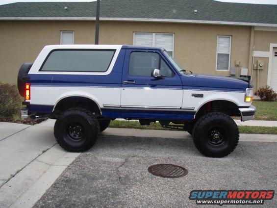 Lifted blue and white Ford Bronco parked on a street