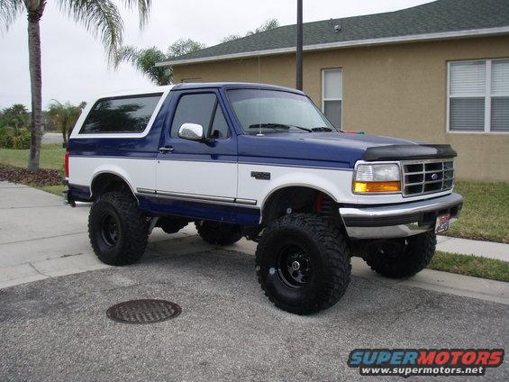 lifted blue and white Ford Bronco parked on a street