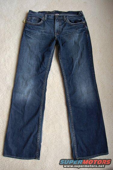 Pair of blue denim jeans laid flat on a carpeted surface