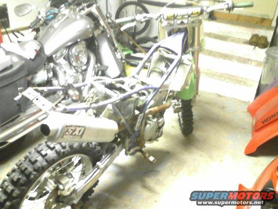 Motorcycle frame, engine, and SXS exhaust. Another motorcycle is partially visible