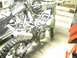 2004 Honda TRX 400 EX - A motorcycle frame is shown with its engine and exhaust system, with another motorcycle in the background.