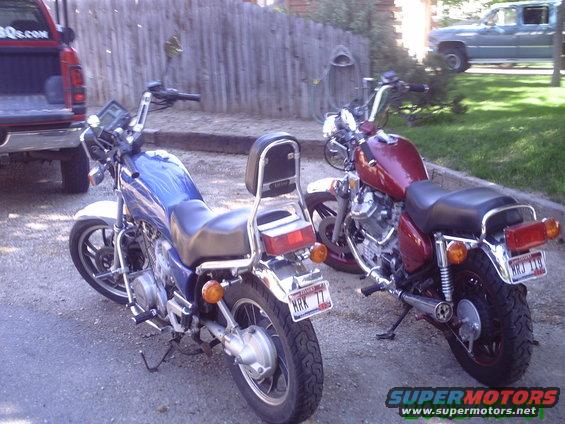 Two motorcycles parked outside, one blue and one red. A red pickup truck is partially visible on the left