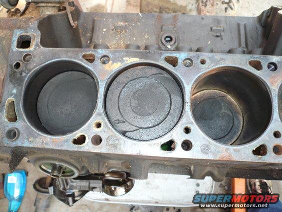 Engine block with three visible pistons, showing wear