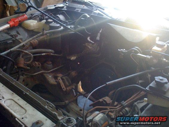 engine bay with parts removed, showing engine block and surrounding components