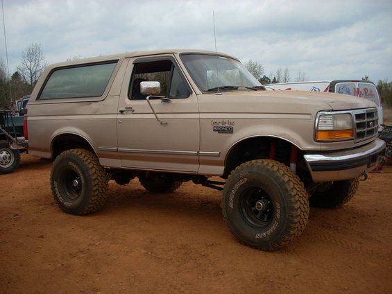 1996 Ford Bronco lifted with large off-road tires, tan paint, side view
