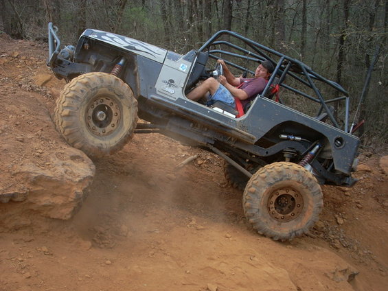 Off-road Jeep Wrangler with roll cage climbing a rocky incline