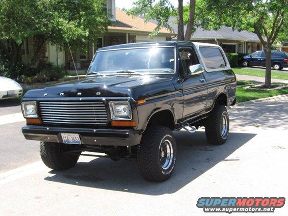 Black Ford Bronco with lifted suspension and chrome wheels parked on a suburban street