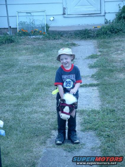 simg1144.jpg son in my cowboy boots and a fishing hat riding stick horse