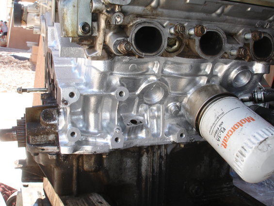 Engine block with a Motorcraft FL-1A oil filter attached. The block is silver and black, with visible bolts and ports