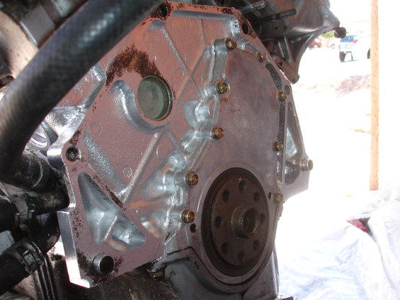 Engine block with a hose and bolts visible