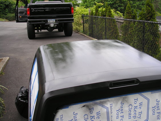 Black pickup truck rear view, with a black vehicle top in the foreground
