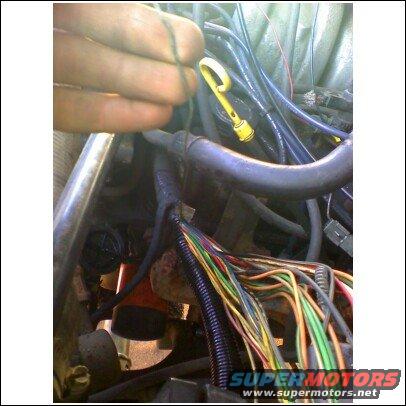 Engine bay with exposed colorful wires and a yellow dipstick handle