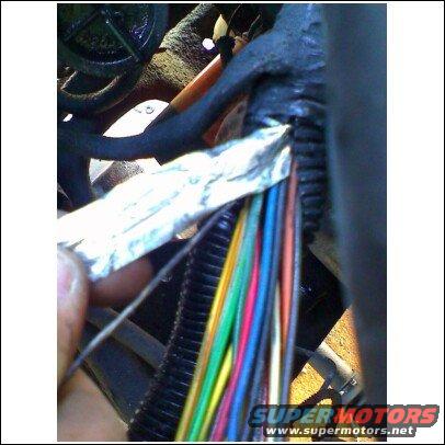 Close-up of a colorful wiring harness with a hand holding foil