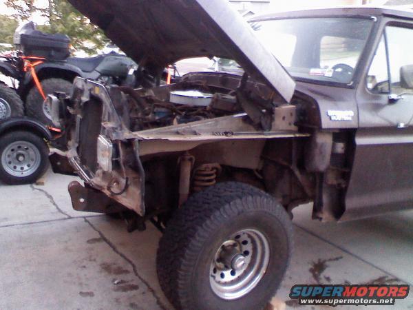 Front end of a 1979 Ford Bronco with hood open, showing engine. ATV and motorcycle in background