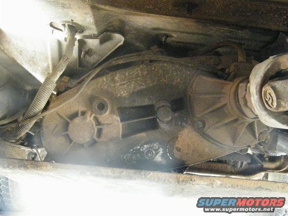 Underside view of a rusty transfer case and driveshaft with visible part numbers