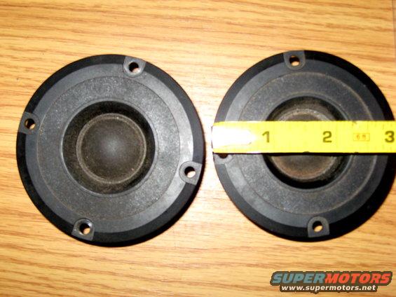 Two car speakers, one measured with a yellow tape measure showing approximately 2.5 inches