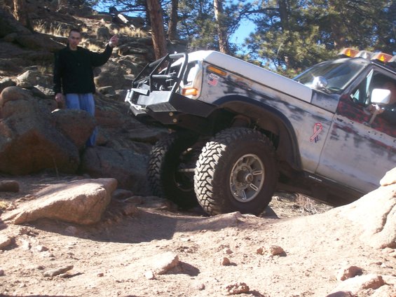 White 1978 Ford Bronco with off-road modifications navigating rocky terrain