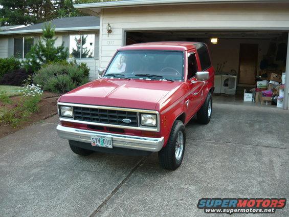 Red SUV parked in driveway, front end visible. House and garage in background