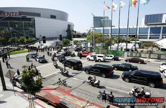 Street scene with police cars, SUVs, motorcycles, and a large building