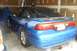 1994 Mazda 626 - Blue coupe with a spoiler and custom bumper text sits in a garage.