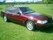 2004 Ford Crown Victoria - This maroon Ford Crown Victoria is parked on a grassy field with a gazebo and trees in the background.