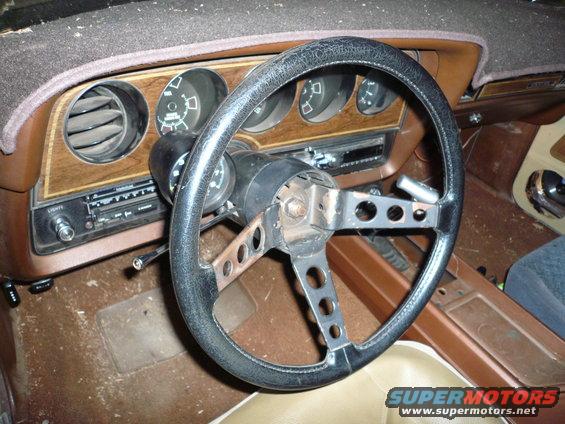 1975 Ford Ranchero interior showing cracked steering wheel, wood-grain dash, and radio