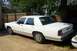 1991 Ford Crown Victoria LTD - A white sedan with tinted windows is parked outdoors on a gravel surface, with a wooden fence behind it.