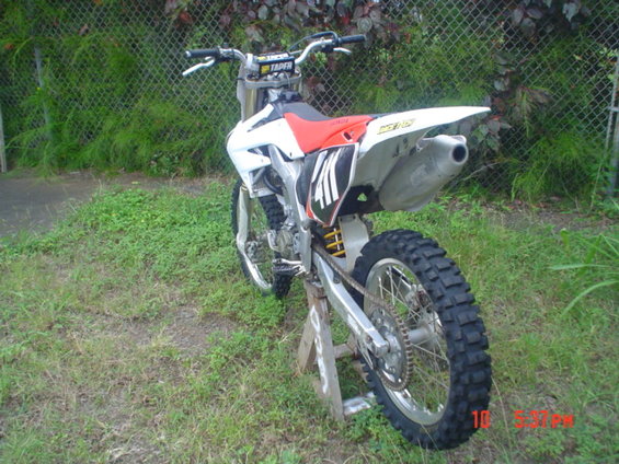 Rear view of a white and red dirt bike on a stand