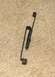 1984 Ford Bronco - A close-up view of a metal clip and spring assembly, likely a vehicle part, on a carpeted surface.