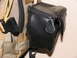 1984 Ford Bronco - A black leather pouch is attached to a tan tactical backpack, showing zippers and straps.