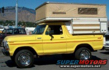 Yellow 1978 Ford Bronco with a tan camper shell, side view, chrome wheels, some rust visible