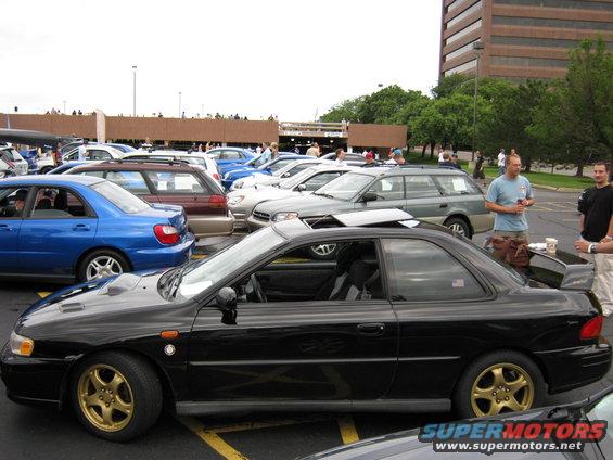 Black 1998 Subaru Legacy coupe with gold wheels and a rear spoiler, parked in a lot