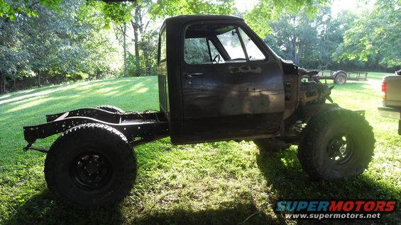 Side view of a black 1980s Dodge pickup truck chassis with cab, missing body panels