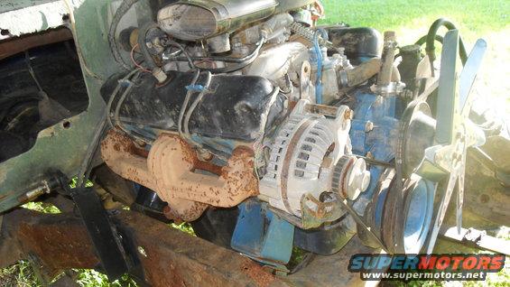 V8 engine with alternator and fan visible, showing rusty exhaust manifold