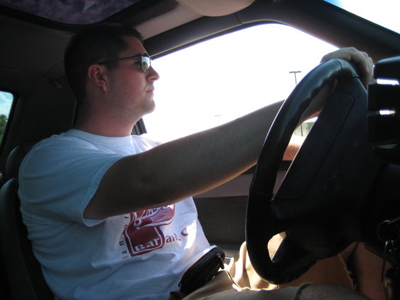 Man wearing sunglasses driving a 1990 Ford Mustang