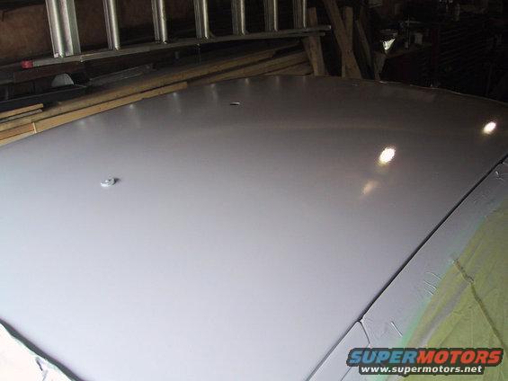Light gray car roof with a small silver antenna base, viewed from above in a garage