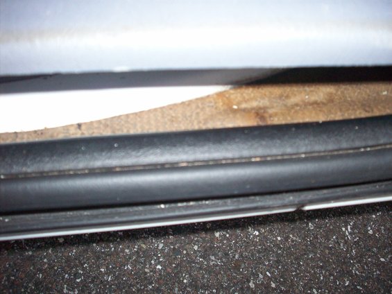 Close-up of a car door seal and interior carpet edge