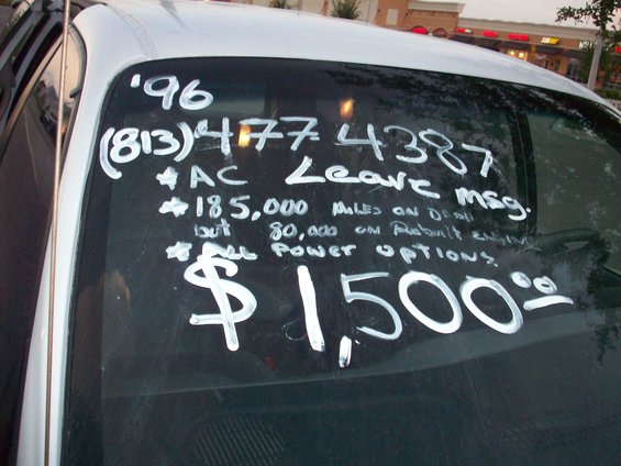 Windshield of a 1996 vehicle with handwritten text listing phone number, mileage, and price