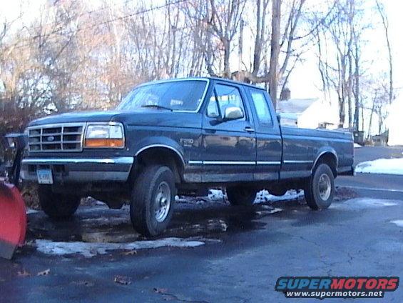 Dark blue 1990s Ford F-250 pickup truck with plow