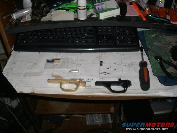 Gun trigger assemblies and small parts laid out on an August calendar page