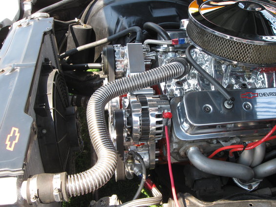 Close-up of a chrome V8 engine, showing air filter, alternator, and exhaust manifold