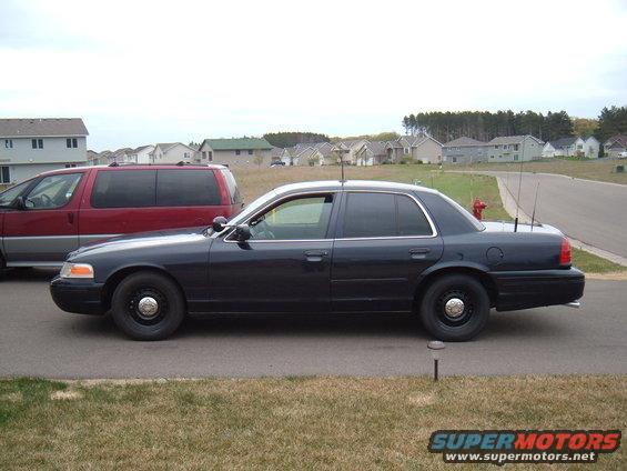Dark police sedan, side view. 2000 Ford Crown Victoria