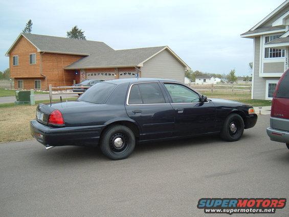 Black 2000 Ford Crown Victoria parked on asphalt in front of a house